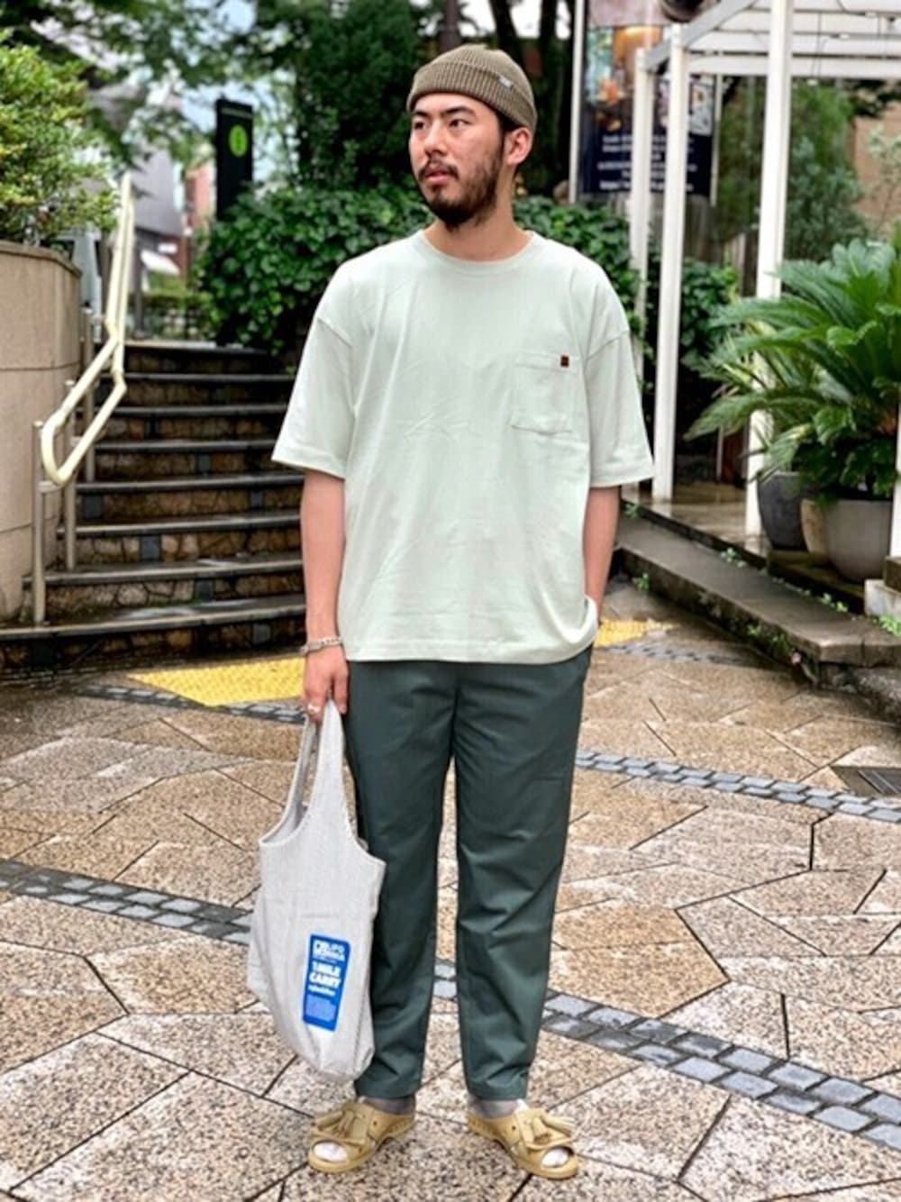 グリーン系のTシャツ/カットソー、グリーン系のその他パンツ、ブルー系のエコバッグ/サブバッグを着用したメンズの夏コーディネートの1枚目の写真