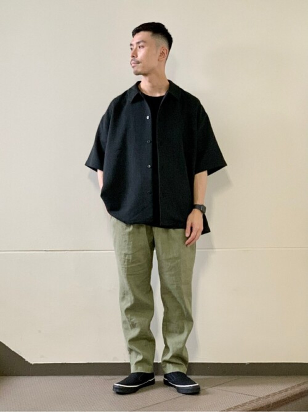 ブラック系のシャツ/ブラウス、グリーン系のスラックス、ホワイト系のスニーカーを着用したメンズの夏コーディネートの1枚目の写真