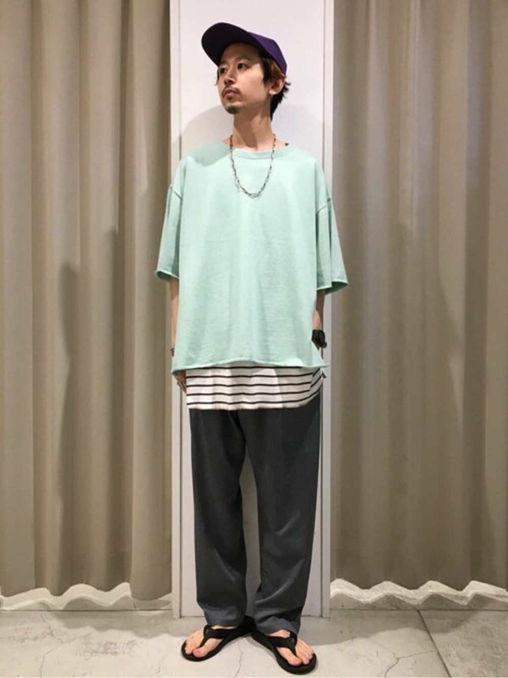 グリーン系のTシャツ/カットソー、ベージュ系のタンクトップ、グレー系のスラックスを着用したメンズの夏コーディネートの1枚目の写真