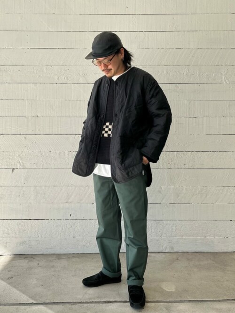 ブラック系のニット/セーター、ホワイト系のTシャツ/カットソー、グリーン系のチノパンツを着用したメンズの冬コーディネートの1枚目の写真