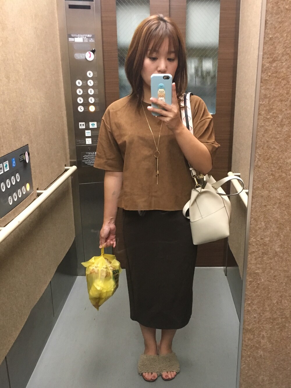 ベージュ系のサンダル、ブラウン系のTシャツ/カットソー、グリーン系のスカートを着用したレディースの秋コーディネートの1枚目の写真