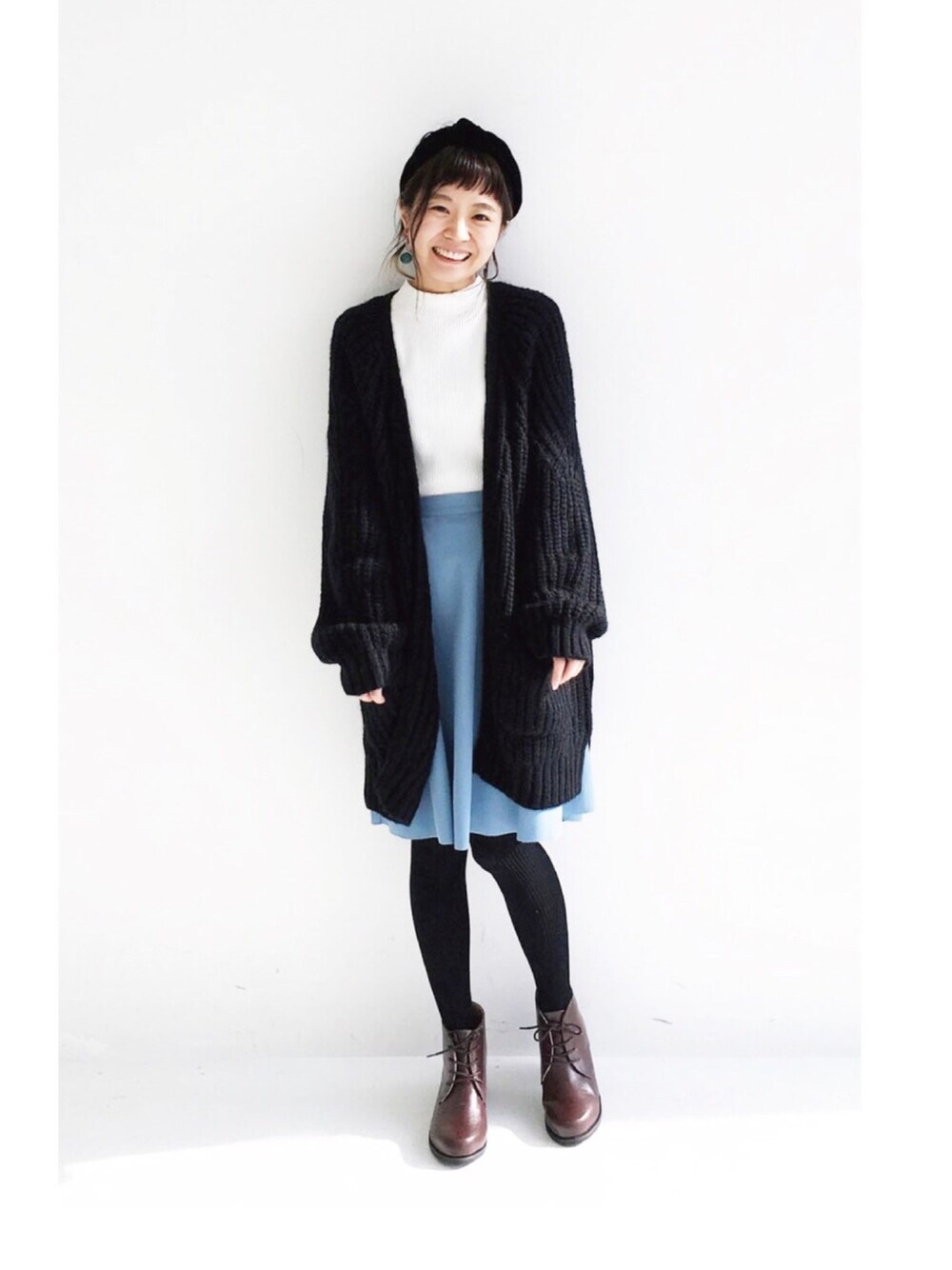 ブラック系のカーディガン/ボレロ、ホワイト系のニット/セーター、グレー系のスカートを着用したレディースの冬コーディネートの1枚目の写真