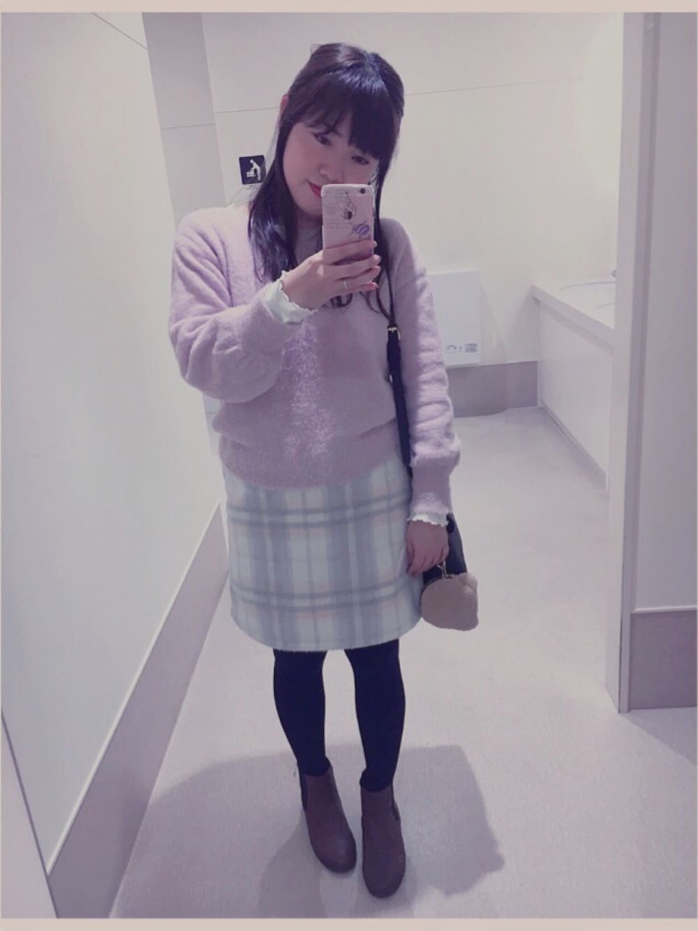 ピンク系のニット/セーター、ホワイト系のスカート、ブラック系のショルダーバッグを着用したレディースの冬コーディネートの1枚目の写真