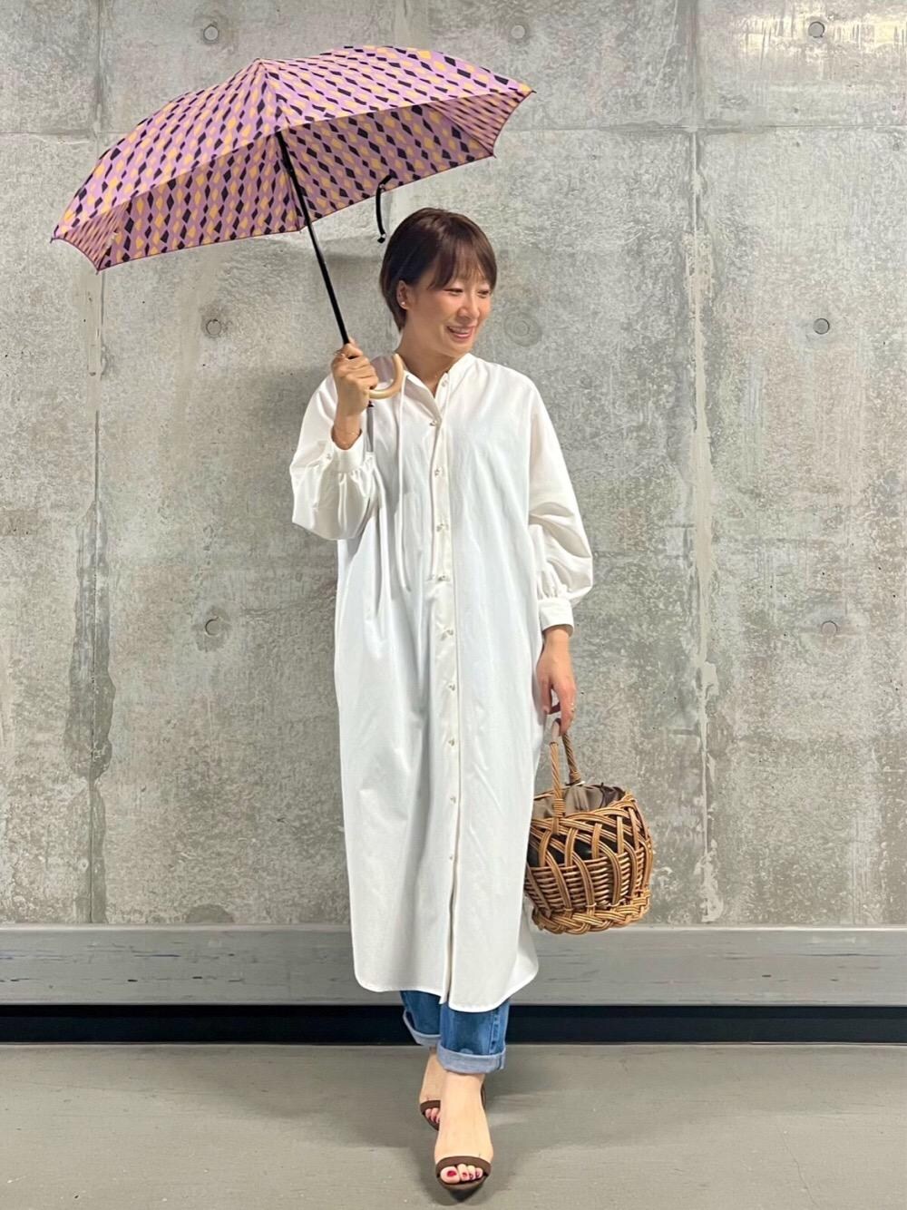 ブルー系のデニムパンツ、ホワイト系のシャツワンピースを着用したレディースの春コーディネートの1枚目の写真