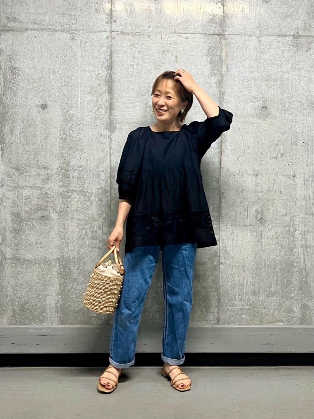 ブルー系のデニムパンツ、ブラック系のシャツ/ブラウス、ベージュ系のかごバッグを着用したレディースの春コーディネートの1枚目の写真