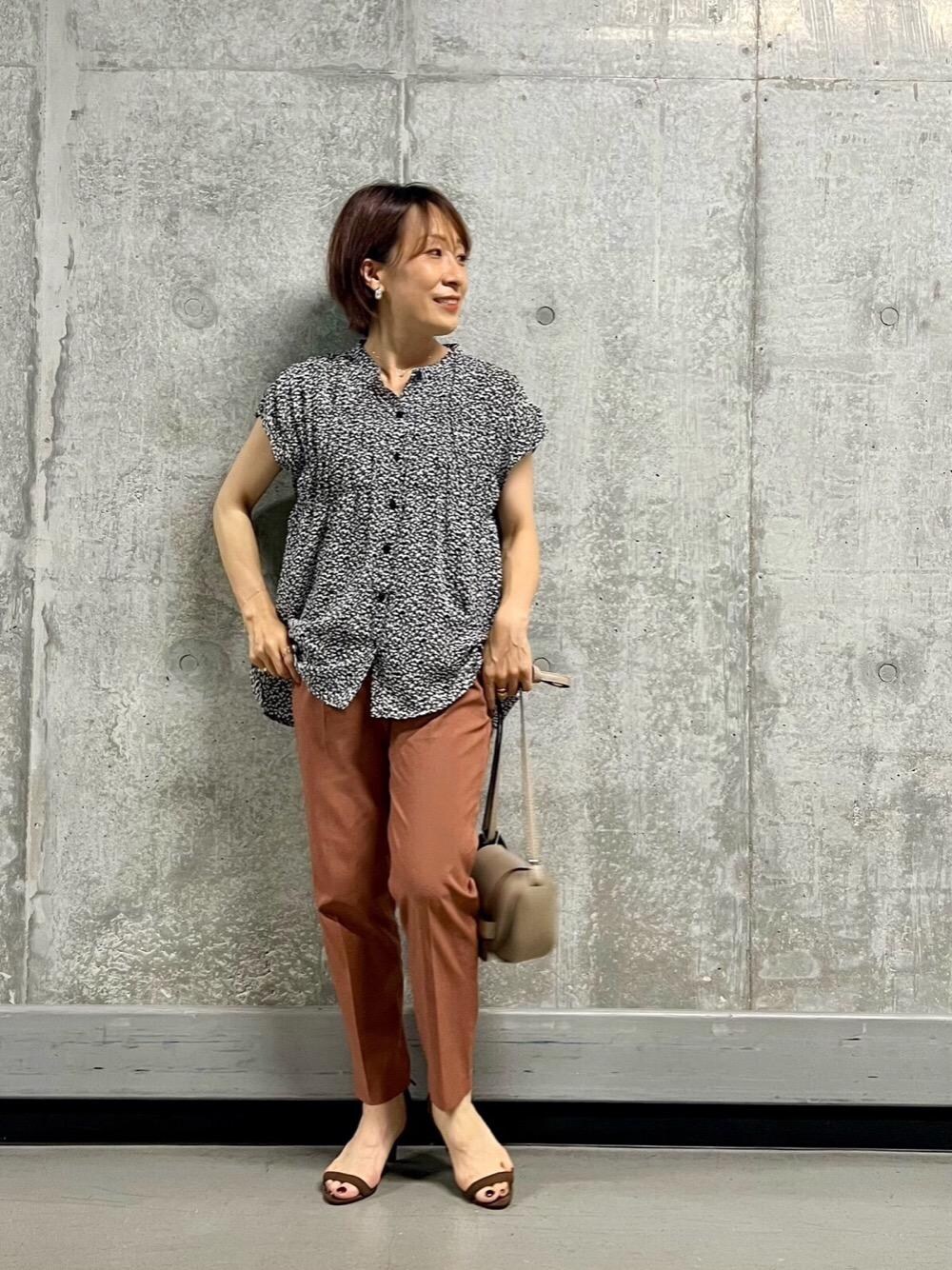 ベージュ系のショルダーバッグ、オレンジ系のスラックスを着用したレディースの夏コーディネートの1枚目の写真