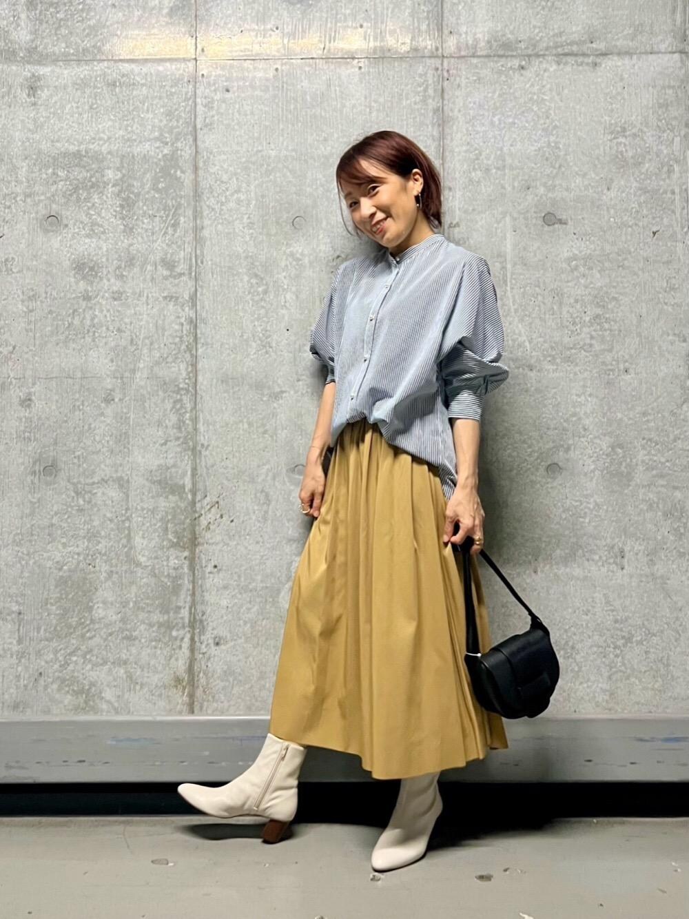 ブラック系のショルダーバッグ、ブルー系のシャツ/ブラウス、グリーン系のスカートを着用したレディースの夏コーディネートの1枚目の写真