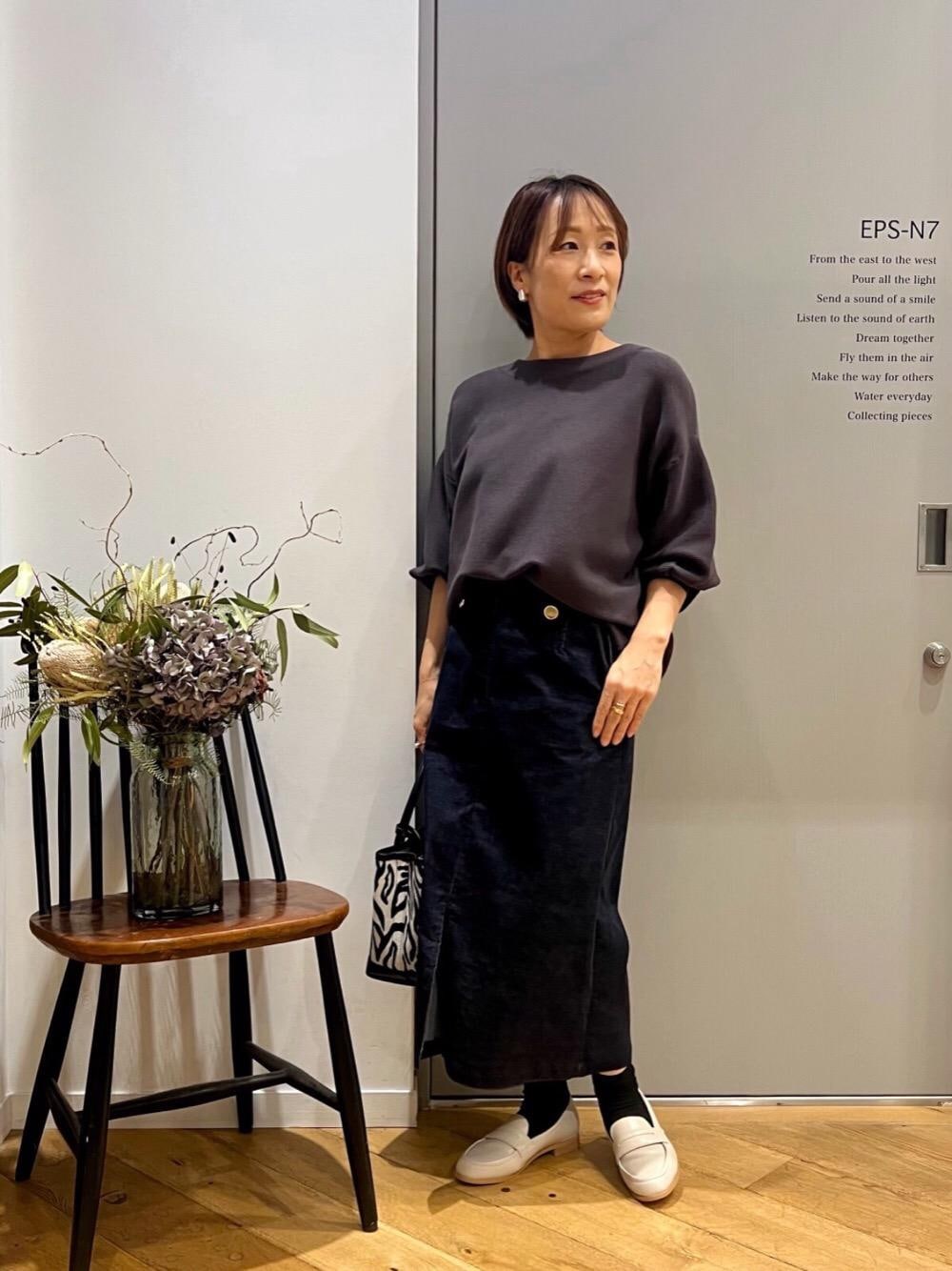 グレー系のニット/セーター、ベージュ系のローファー、ブルー系のスカートを着用したレディースの秋コーディネートの1枚目の写真