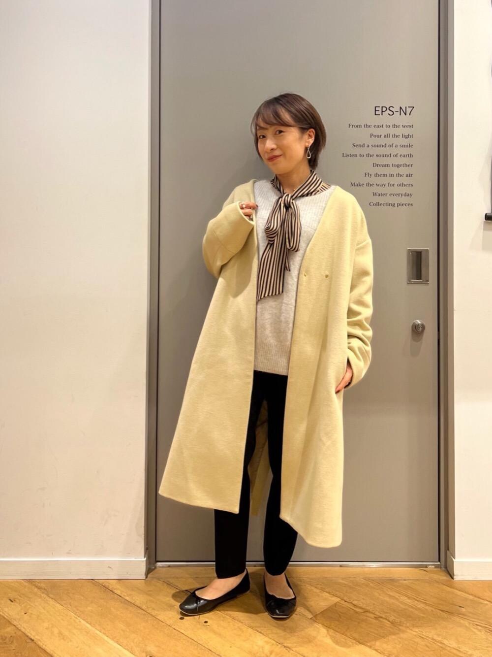 グレー系のニット/セーター、ブラック系のスラックス、イエロー系のノーカラーコートを着用したレディースの秋コーディネートの1枚目の写真