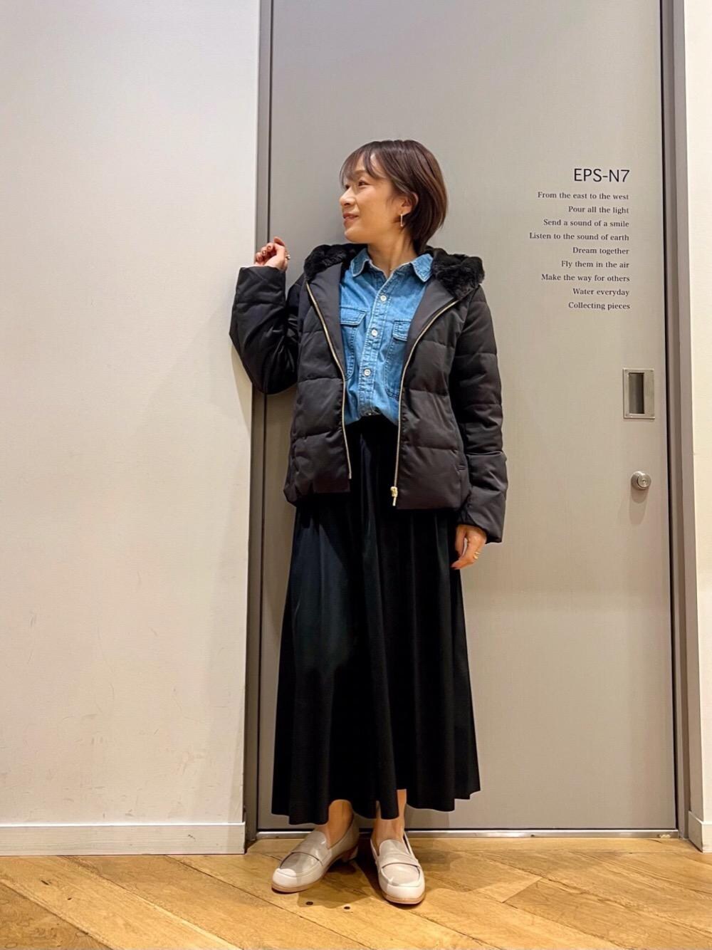 ブルー系のシャツ/ブラウス、ブルー系のスカート、ブラック系のダウンジャケット/コートを着用したレディースの秋コーディネートの1枚目の写真