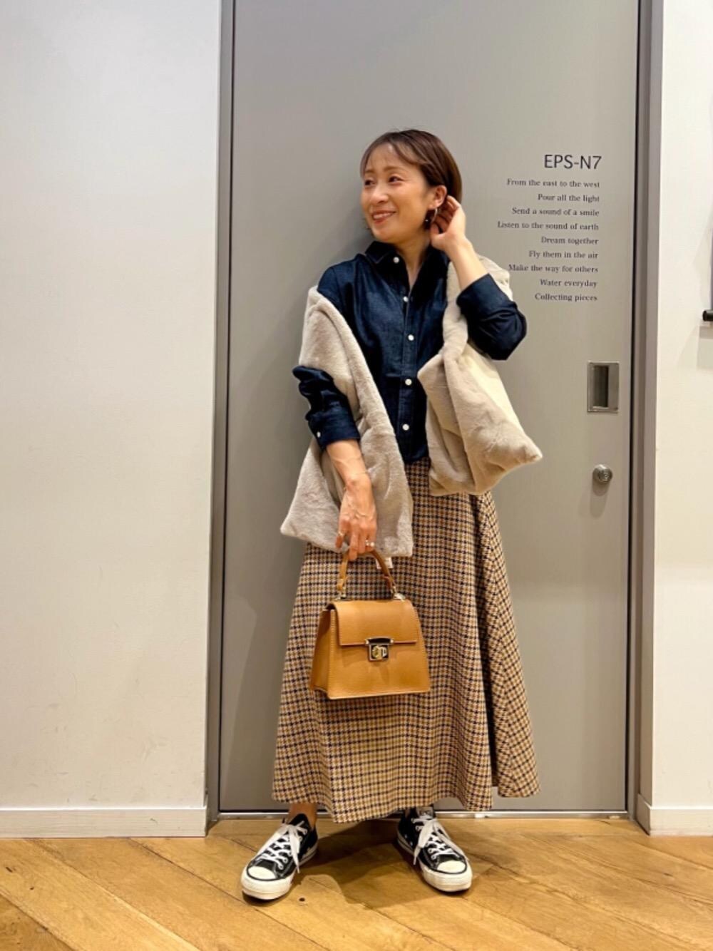 ベージュ系のスカート、イエロー系のショルダーバッグ、ブルー系のシャツ/ブラウスを着用したレディースの秋コーディネートの1枚目の写真