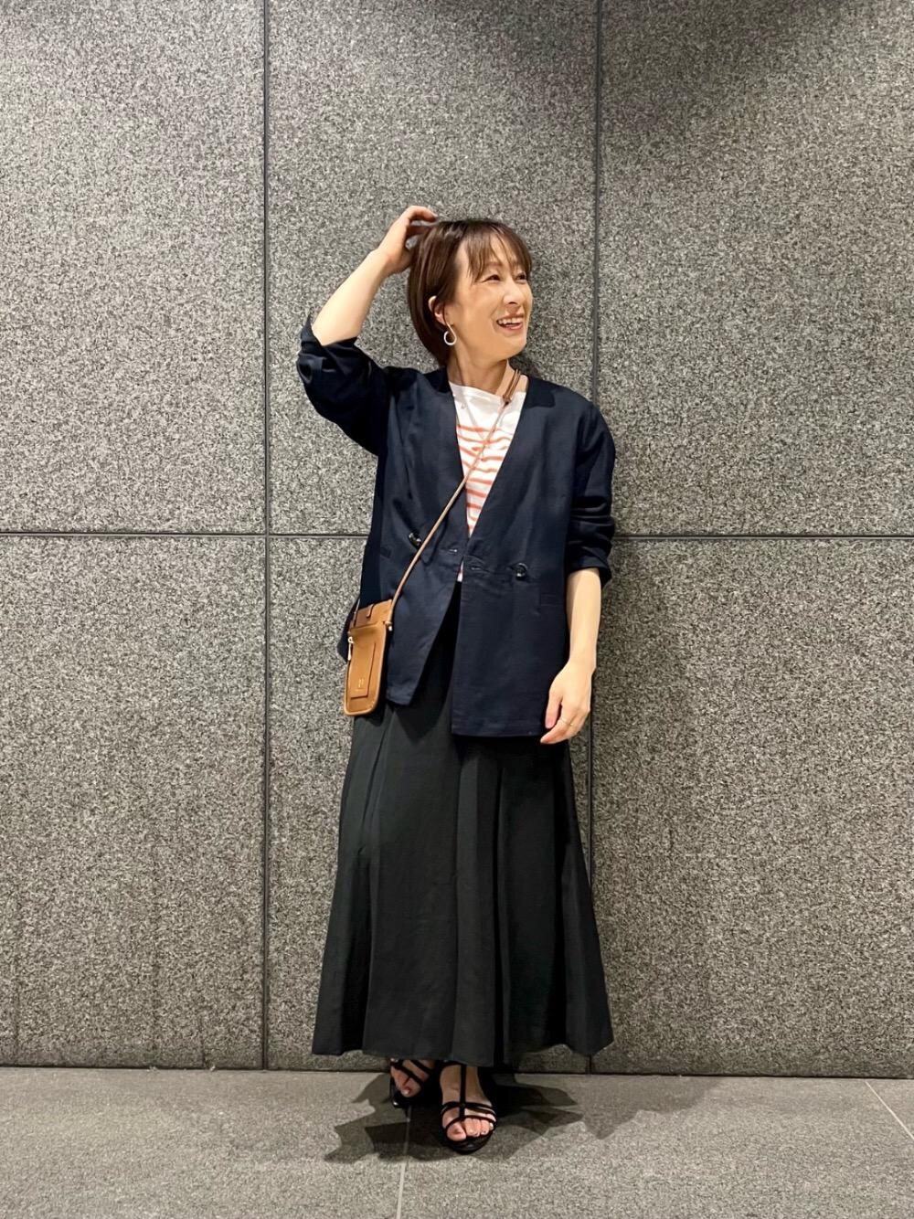 イエロー系のショルダーバッグ、ブルー系のノーカラージャケット、ブラック系のスカートを着用したレディースの春コーディネートの1枚目の写真