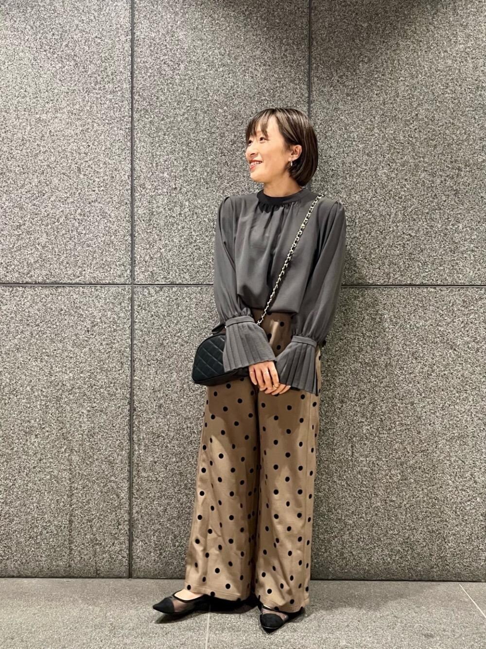 ブラック系のショルダーバッグ、ブラウン系のその他パンツ、グレー系のシャツ/ブラウスを着用したレディースの秋コーディネートの1枚目の写真