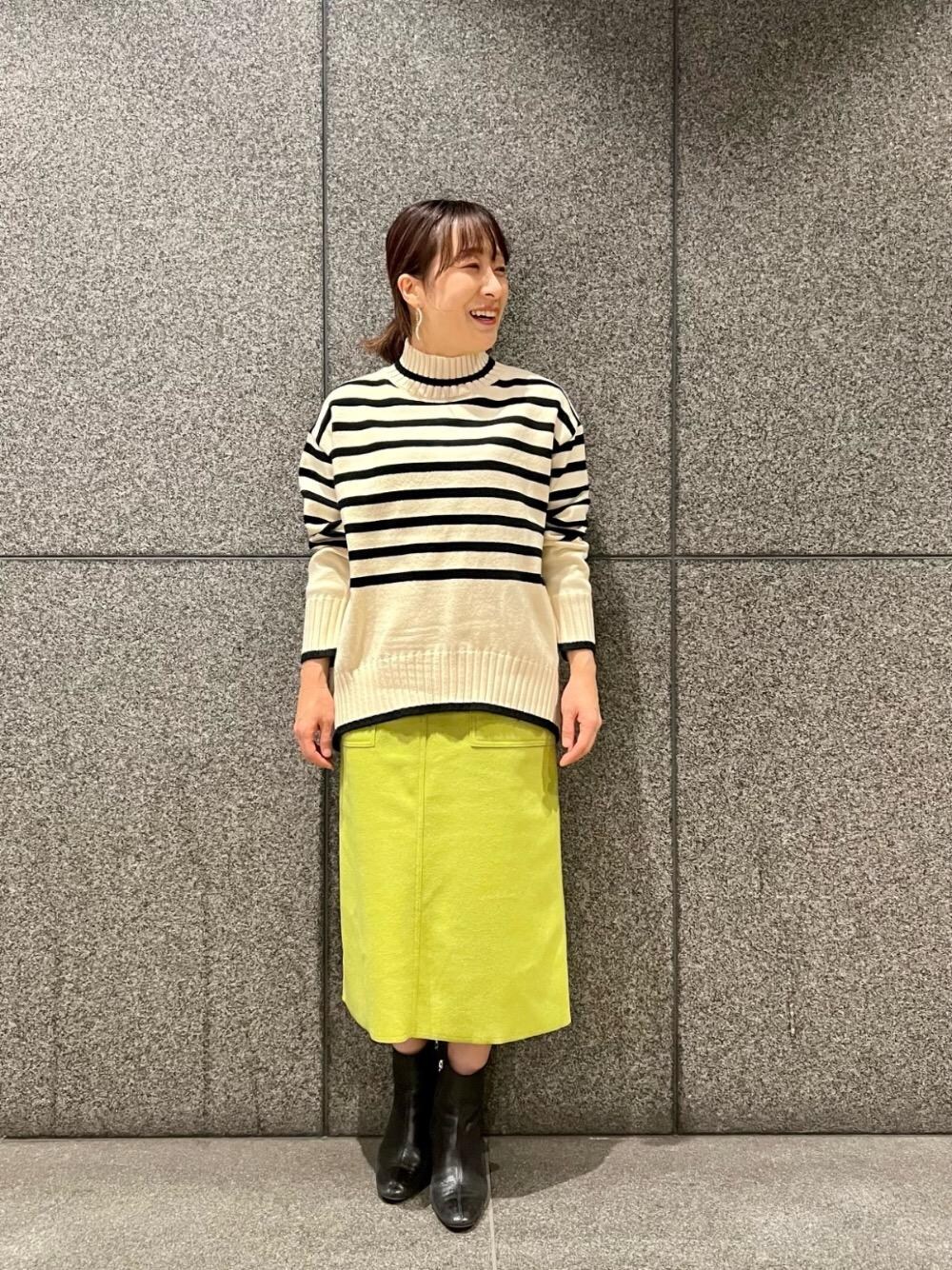 グリーン系のスカート、ホワイト系のニット/セーターを着用したレディースの冬コーディネートの1枚目の写真