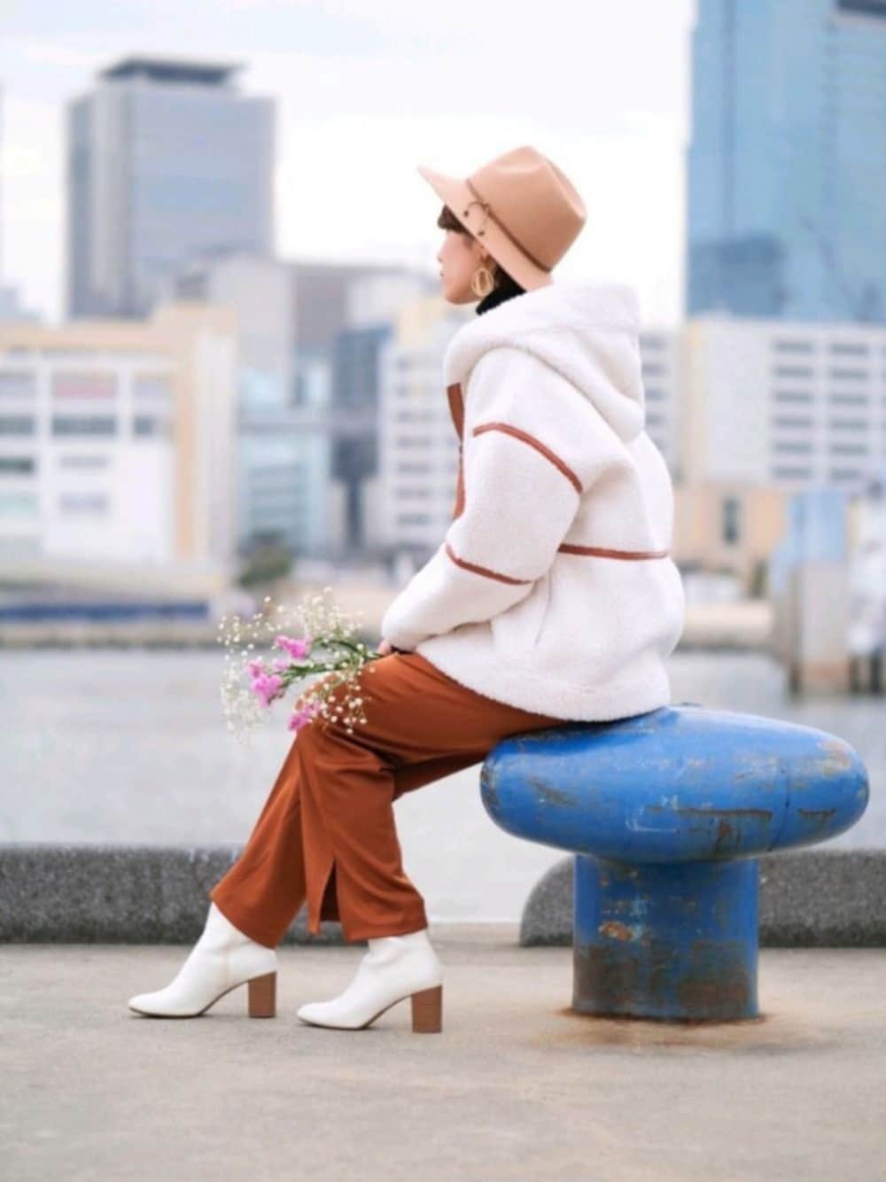 ホワイト系のブルゾン、ブラック系のニット/セーター、ブラウン系のパンツを着用したレディースの冬コーディネートの1枚目の写真