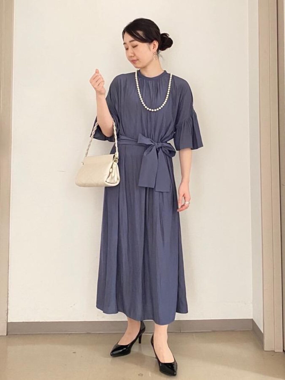 ブラック系のパンプス、グレー系のワンピース、ベージュ系のショルダーバッグを着用したレディースの秋コーディネートの1枚目の写真