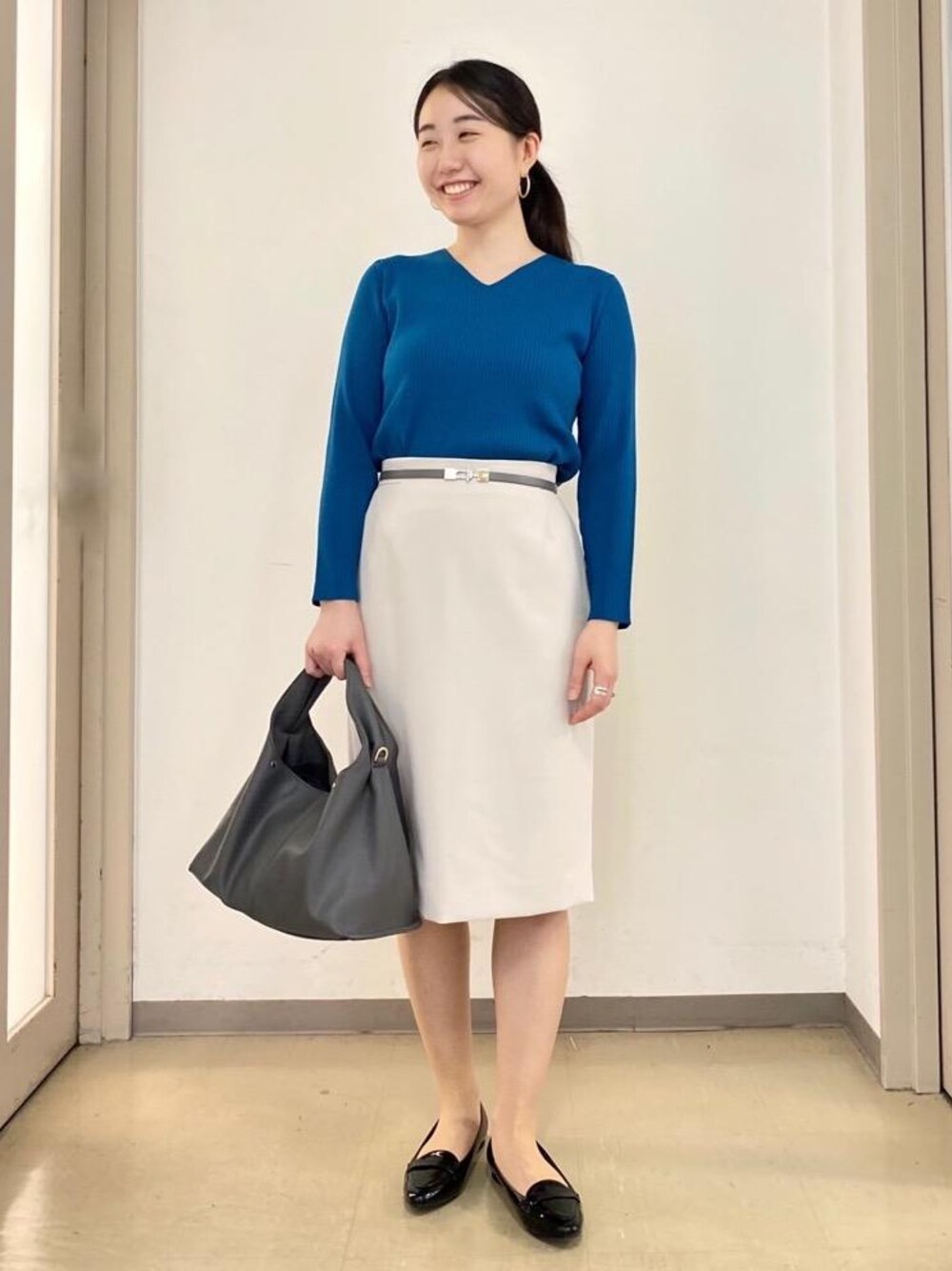 ブラック系のローファー、グレー系のショルダーバッグ、ベージュ系のスカートを着用したレディースの秋コーディネートの1枚目の写真