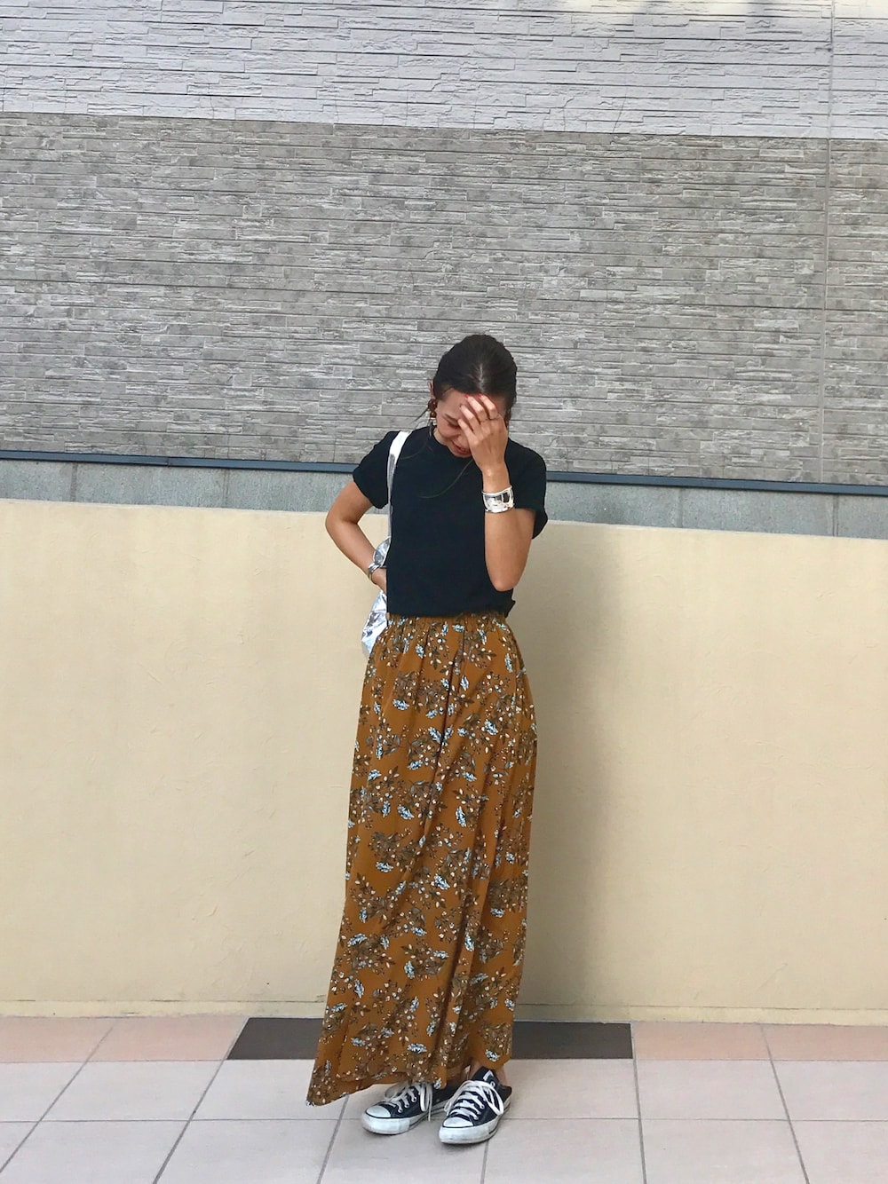 ホワイト系のTシャツ/カットソー、イエロー系のスカート、ブラック系のスニーカーを着用したレディースの夏コーディネートの1枚目の写真