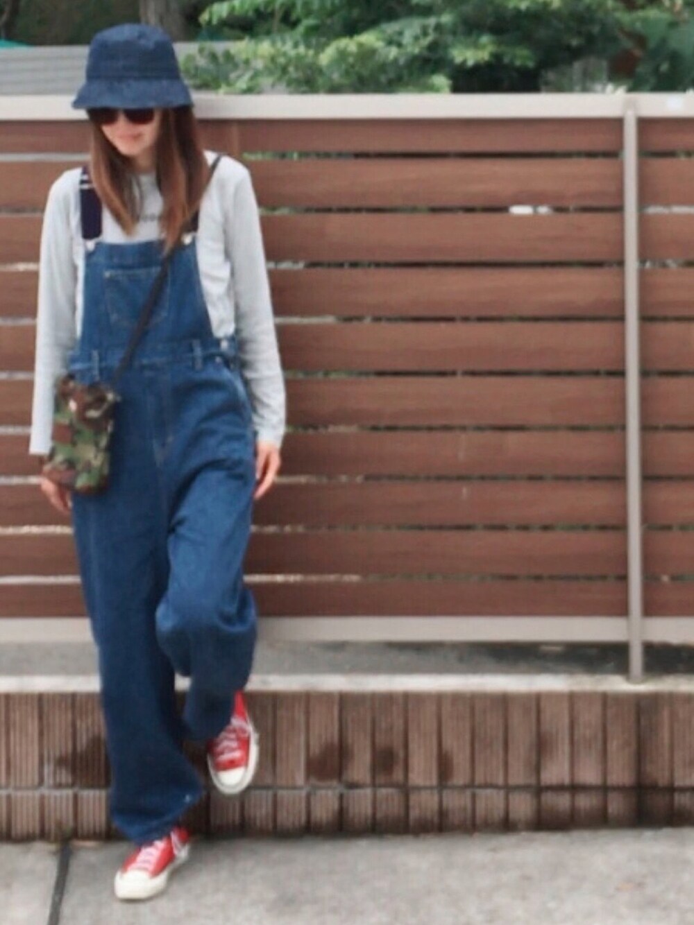 レッド系のスニーカー、ブルー系のサロペット/オーバーオール、グレー系のTシャツ/カットソーを着用したレディースの夏コーディネートの1枚目の写真