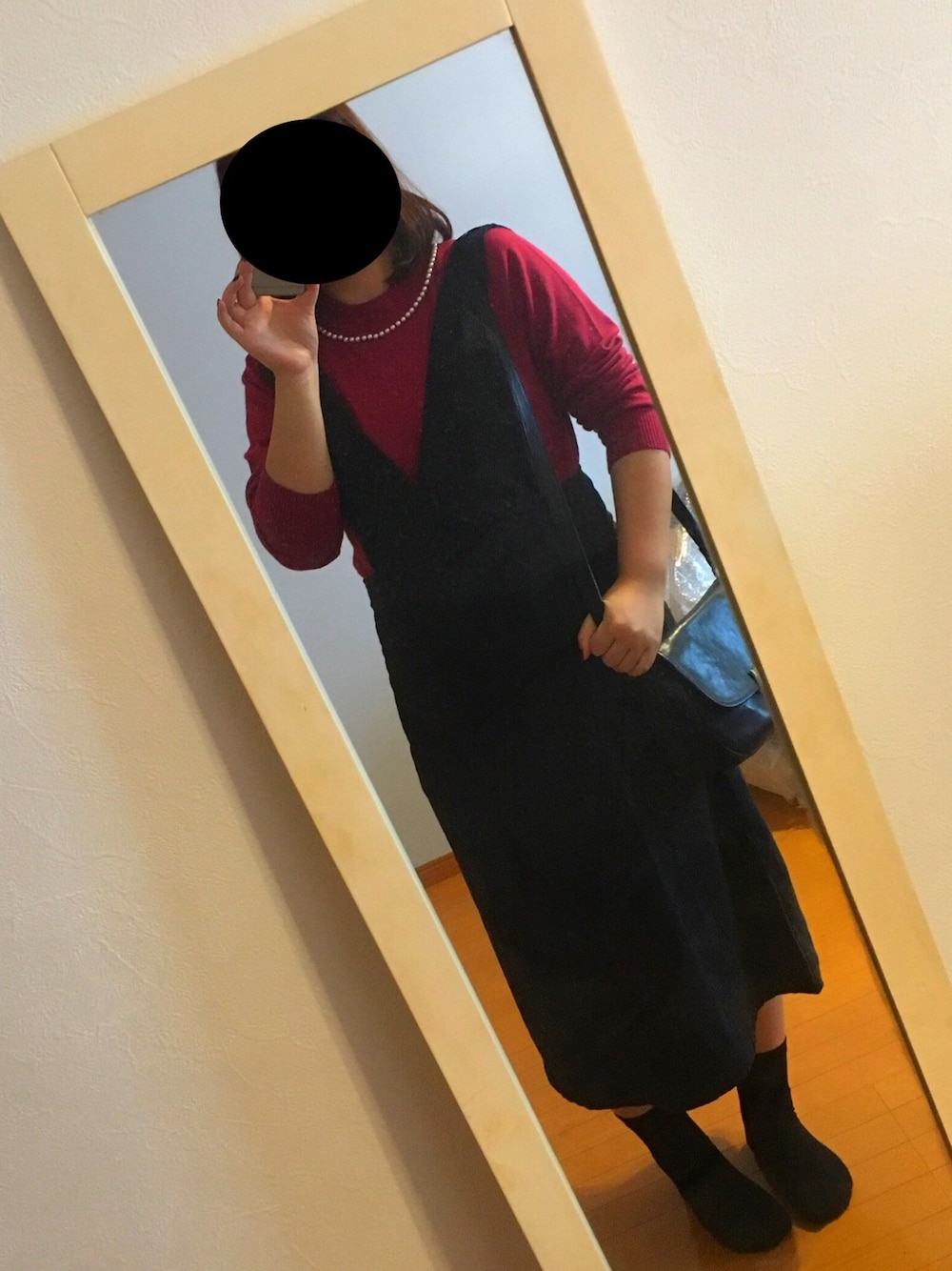 ブラック系のジャンパースカート、レッド系のニット/セーター、ブラック系のショルダーバッグを着用したレディースの秋コーディネートの1枚目の写真