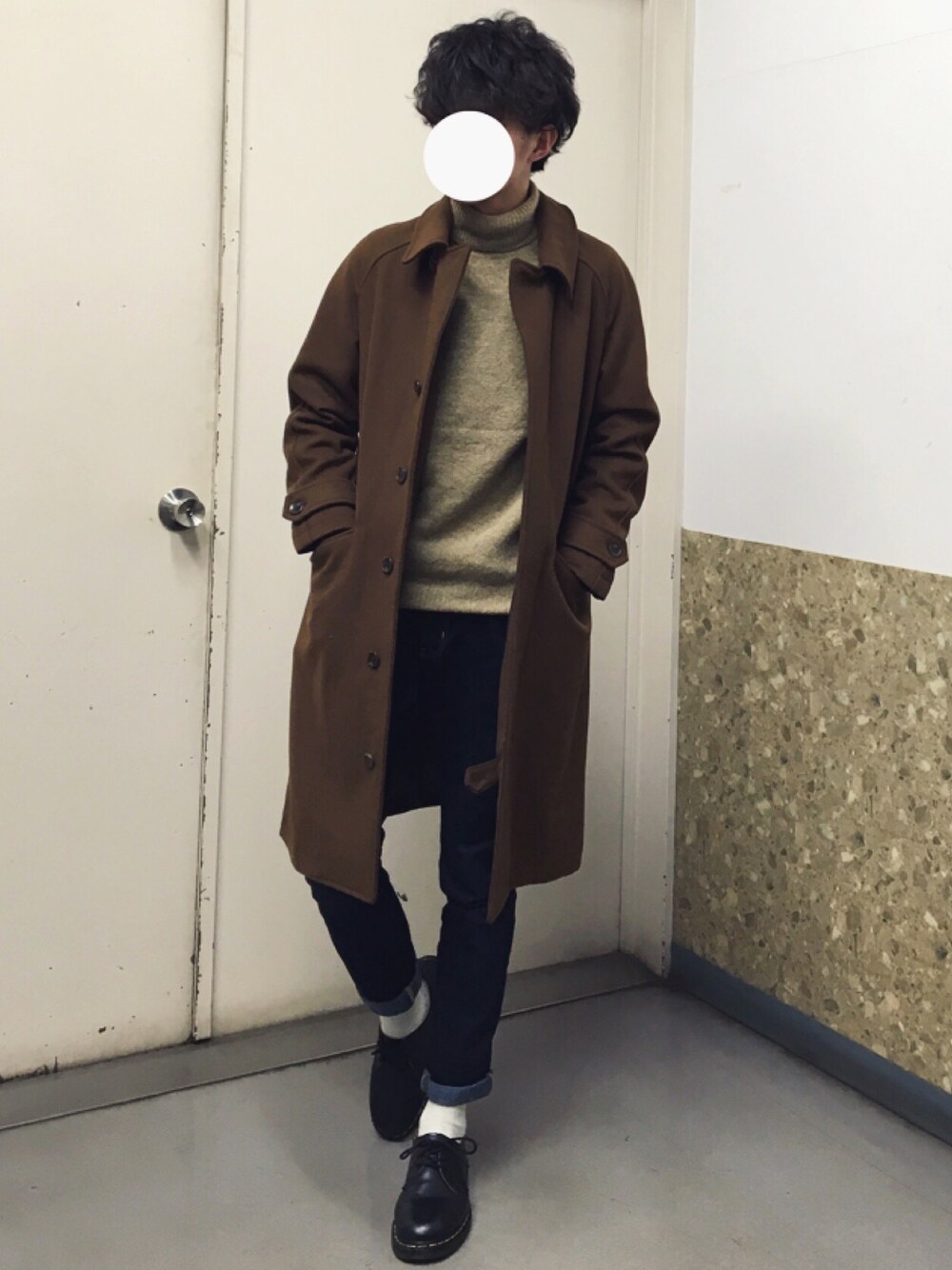 イエロー系のステンカラーコート、ベージュ系のニット/セーター、ブルー系のパンツを着用したメンズの冬コーディネートの1枚目の写真