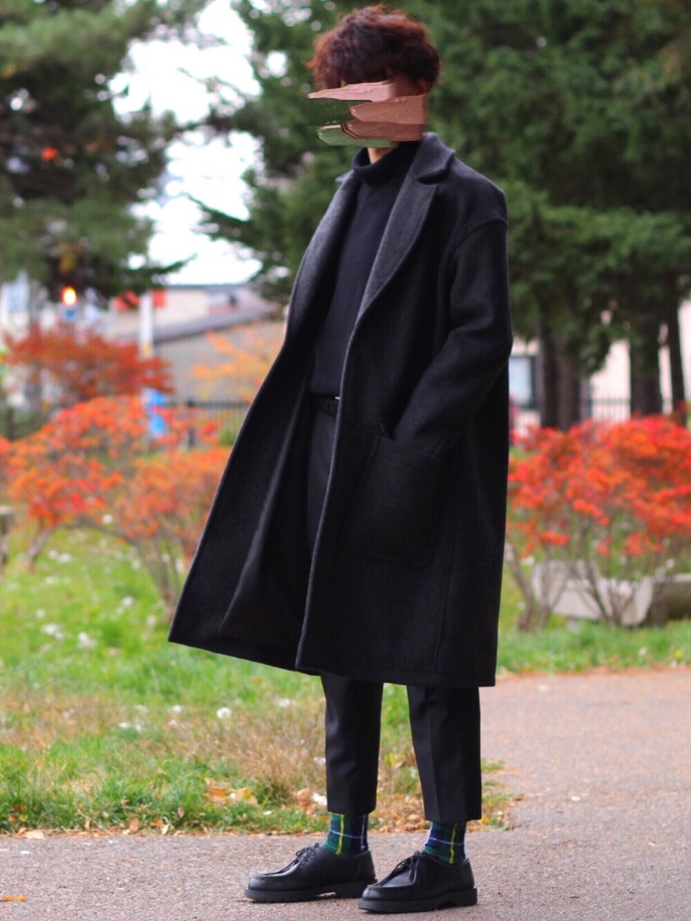 グレー系のチェスターコート、ブラック系のニット/セーター、ブラック系のスラックスを着用したメンズの秋コーディネートの1枚目の写真