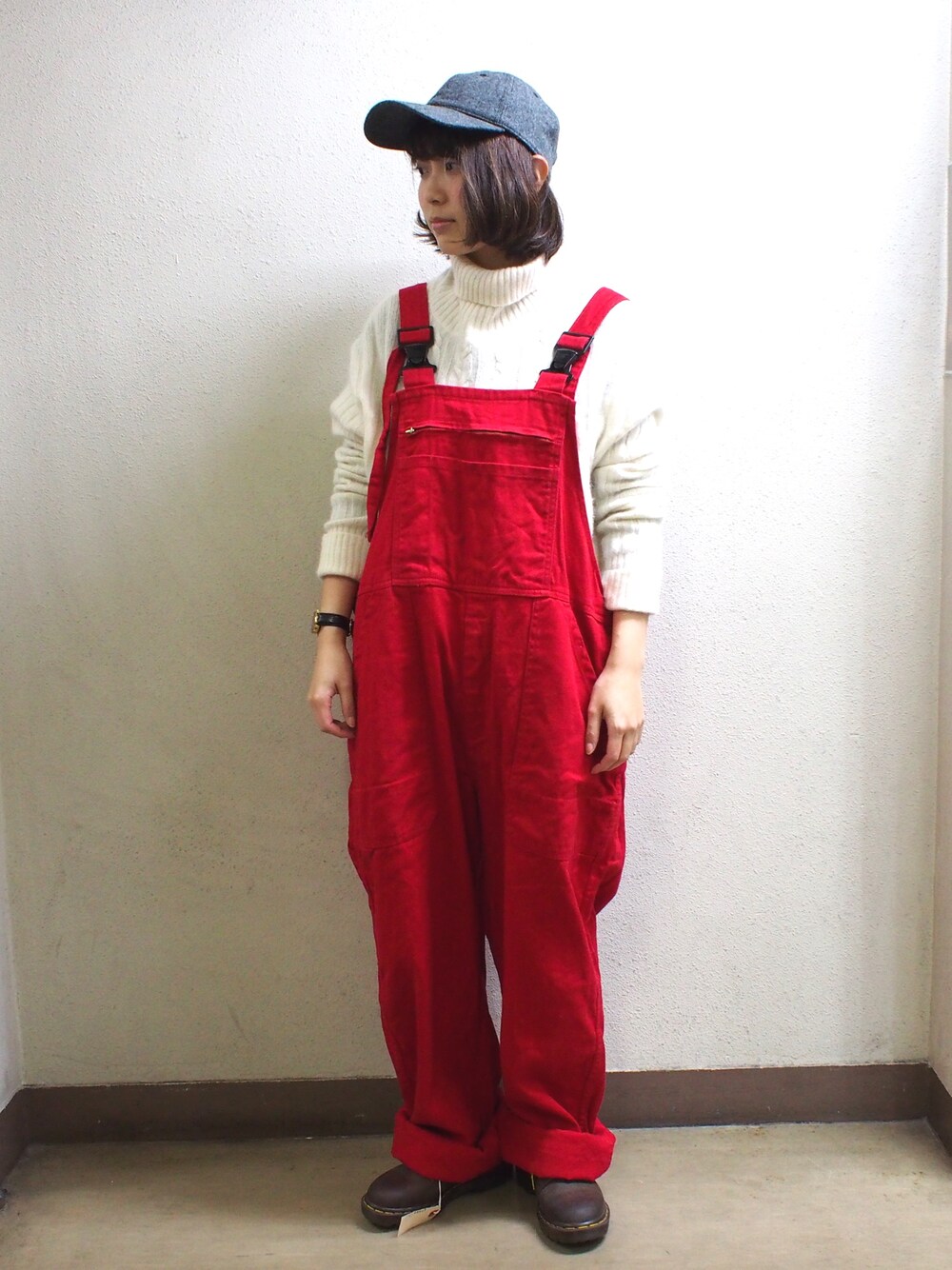 レッド系のサロペット/オーバーオール、ホワイト系のニット/セーター、ブラウン系のブーツを着用したレディースの冬コーディネートの1枚目の写真