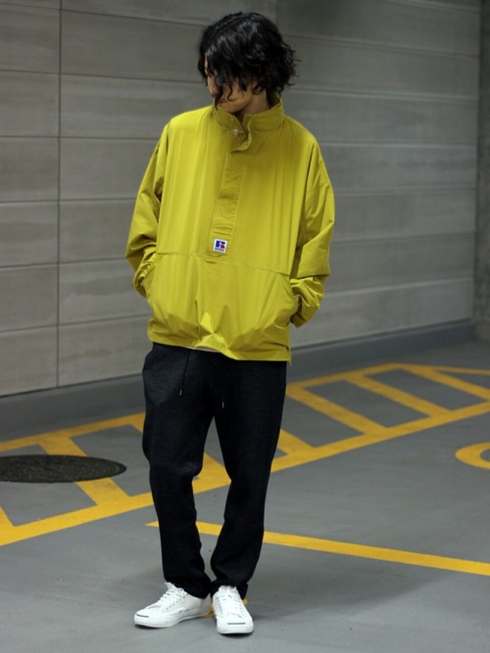 イエロー系のブルゾン、ブラック系のスラックス、ホワイト系のスニーカーを着用したメンズの夏コーディネートの1枚目の写真