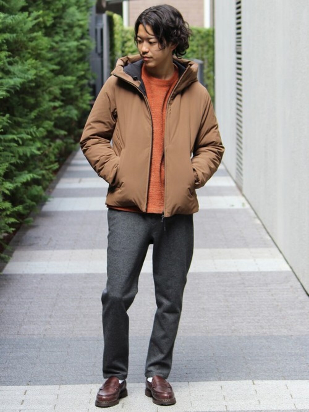 ブラウン系のダウンジャケット/コート、レッド系のニット/セーター、グレー系のスラックスを着用したメンズの秋コーディネートの1枚目の写真