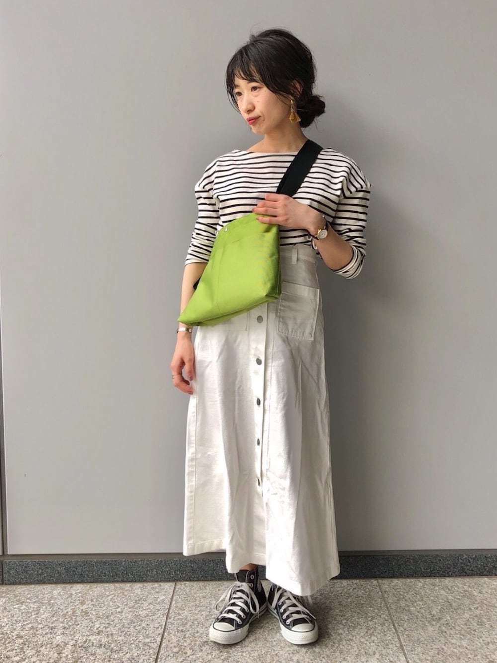 ブラック系のTシャツ/カットソー、ホワイト系のスカート、グリーン系のショルダーバッグを着用したレディースの春コーディネートの1枚目の写真