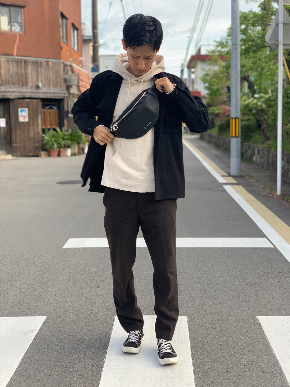 ブラウン系のパンツ、ブラック系のスニーカー、ブラック系のその他アウターを着用したメンズの春コーディネートの1枚目の写真