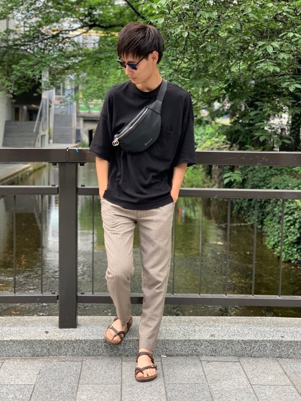 ブラウン系のサンダル、ベージュ系のスラックス、ブラック系のTシャツ/カットソーを着用したメンズの春コーディネートの1枚目の写真