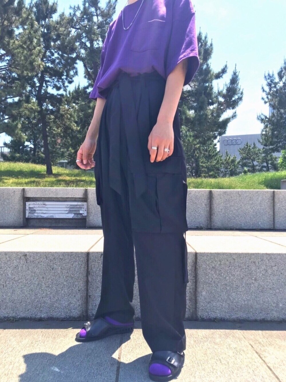 ブラック系のカーゴパンツ、パープル系のTシャツ/カットソー、ブラック系のサンダルを着用したメンズの春コーディネートの1枚目の写真
