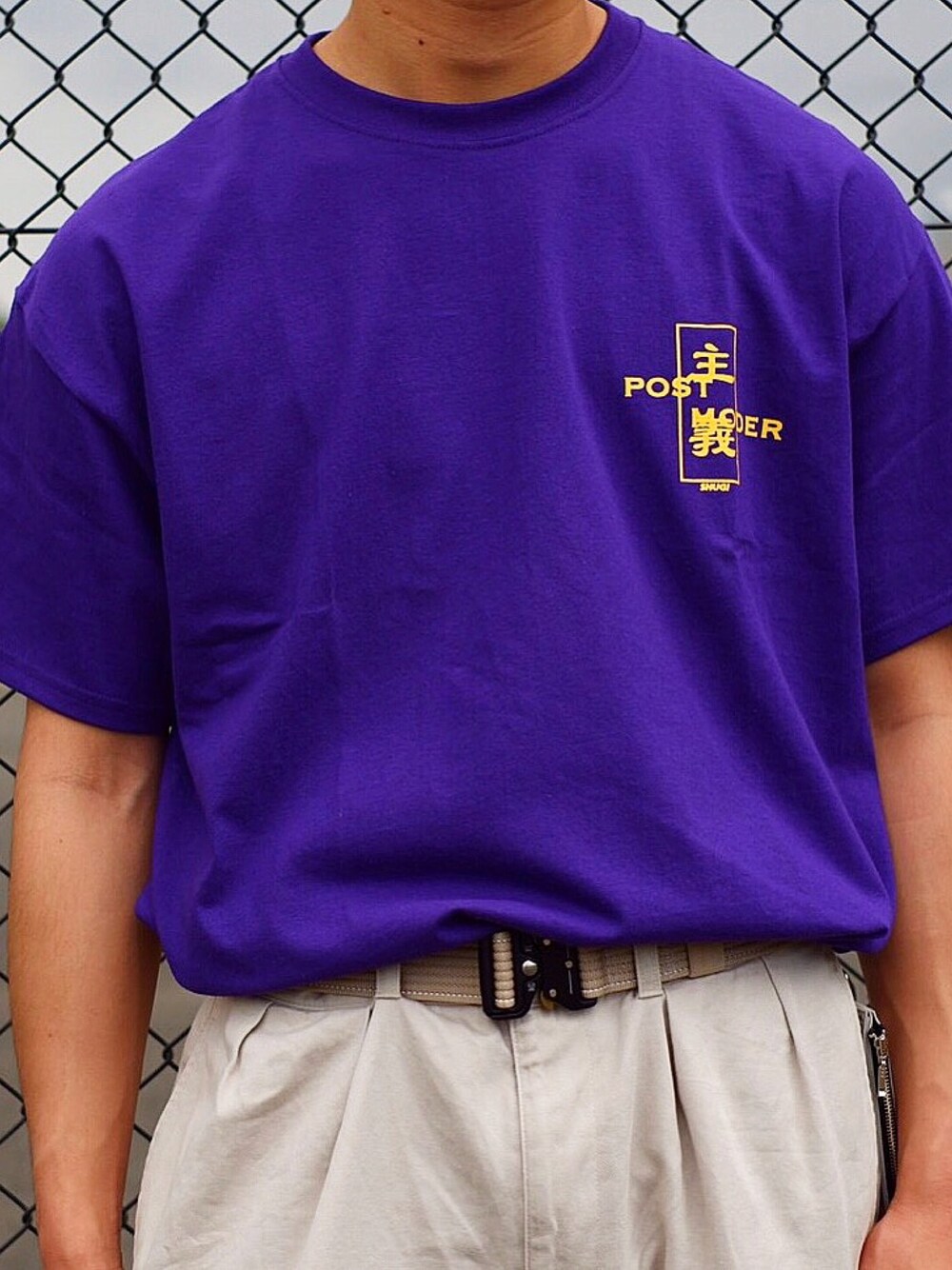 パープル系のトップス、ベージュ系のアクセサリーを着用したメンズの春コーディネートの1枚目の写真