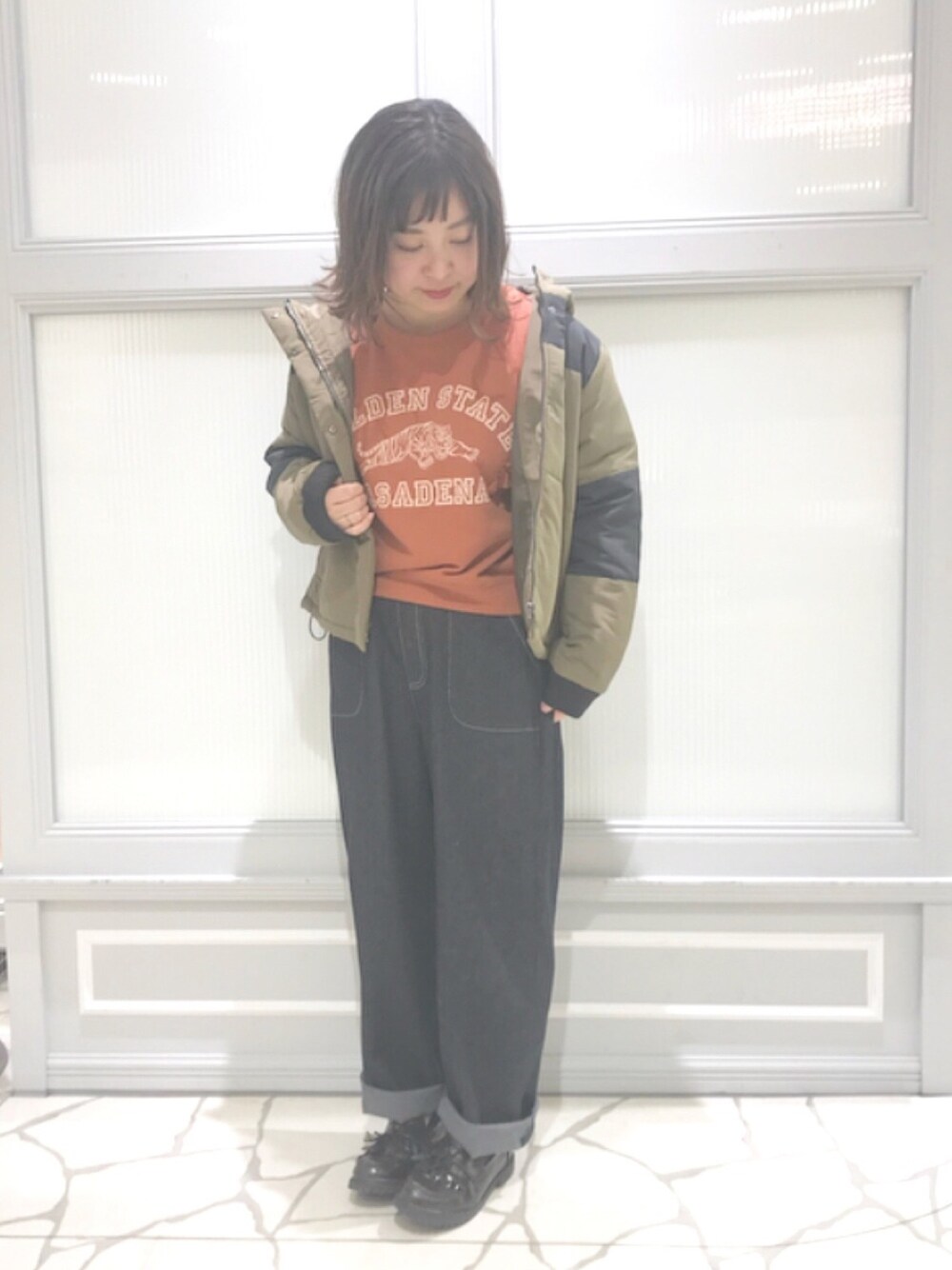 レッド系のTシャツ/カットソー、グリーン系のその他アウター、ブラック系のパンツを着用したレディースの冬コーディネートの1枚目の写真