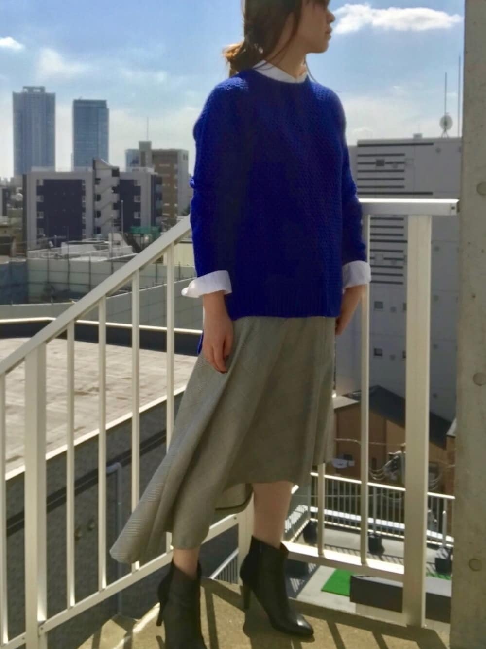 ブルー系のニット/セーター、ホワイト系のシャツ/ブラウス、グレー系のスカートを着用したレディースの秋コーディネートの1枚目の写真