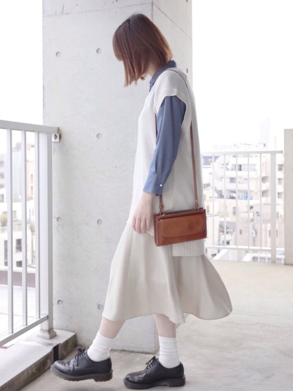 ブルー系のシャツ/ブラウス、ホワイト系のベスト、ベージュ系のスカートを着用したレディースの春コーディネートの1枚目の写真