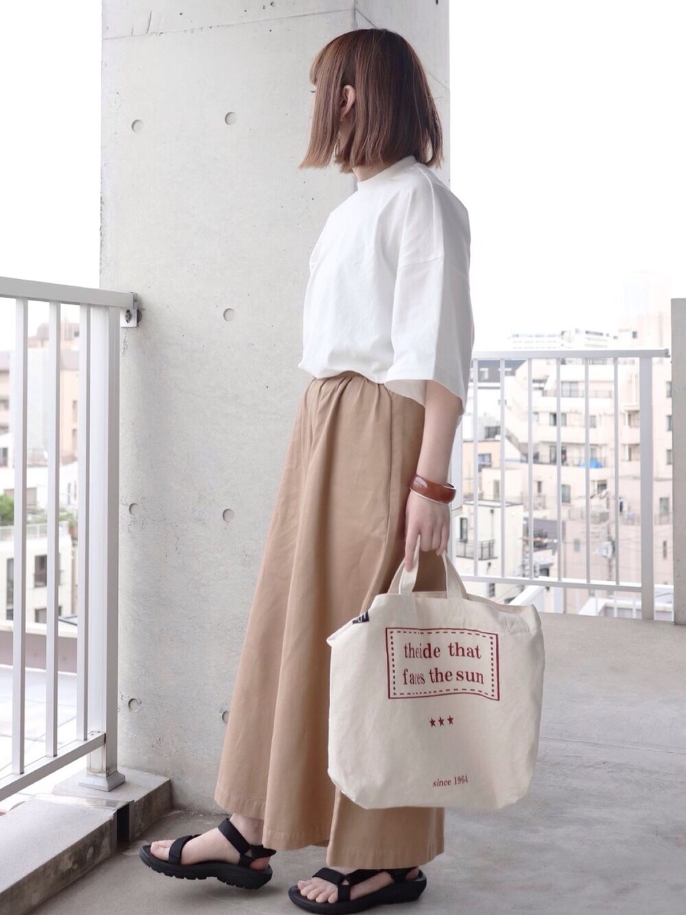 ベージュ系のその他パンツ、ホワイト系のTシャツ/カットソー、ブラック系のサンダルを着用したレディースの春コーディネートの1枚目の写真