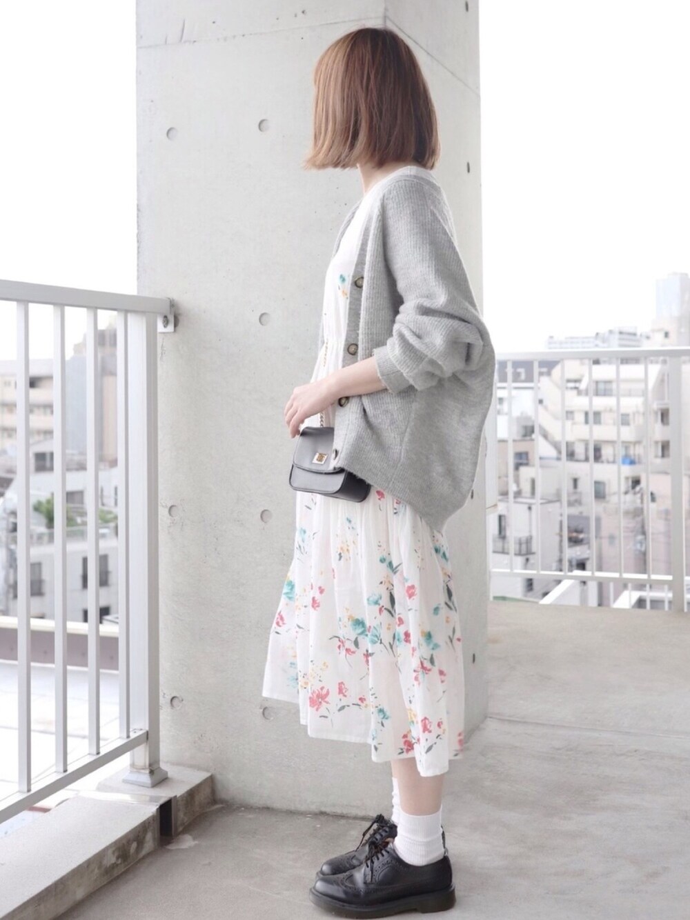 ホワイト系のワンピース、グレー系のカーディガン/ボレロ、ブラック系のショルダーバッグを着用したレディースの春コーディネートの1枚目の写真