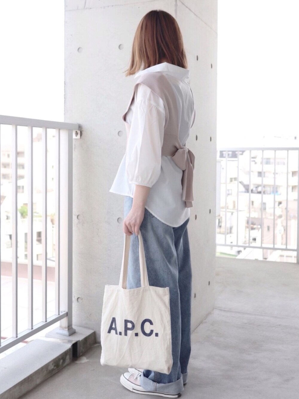 グレー系のシャツ/ブラウス、ブルー系のデニムパンツ、ベージュ系のスニーカーを着用したレディースの春コーディネートの1枚目の写真