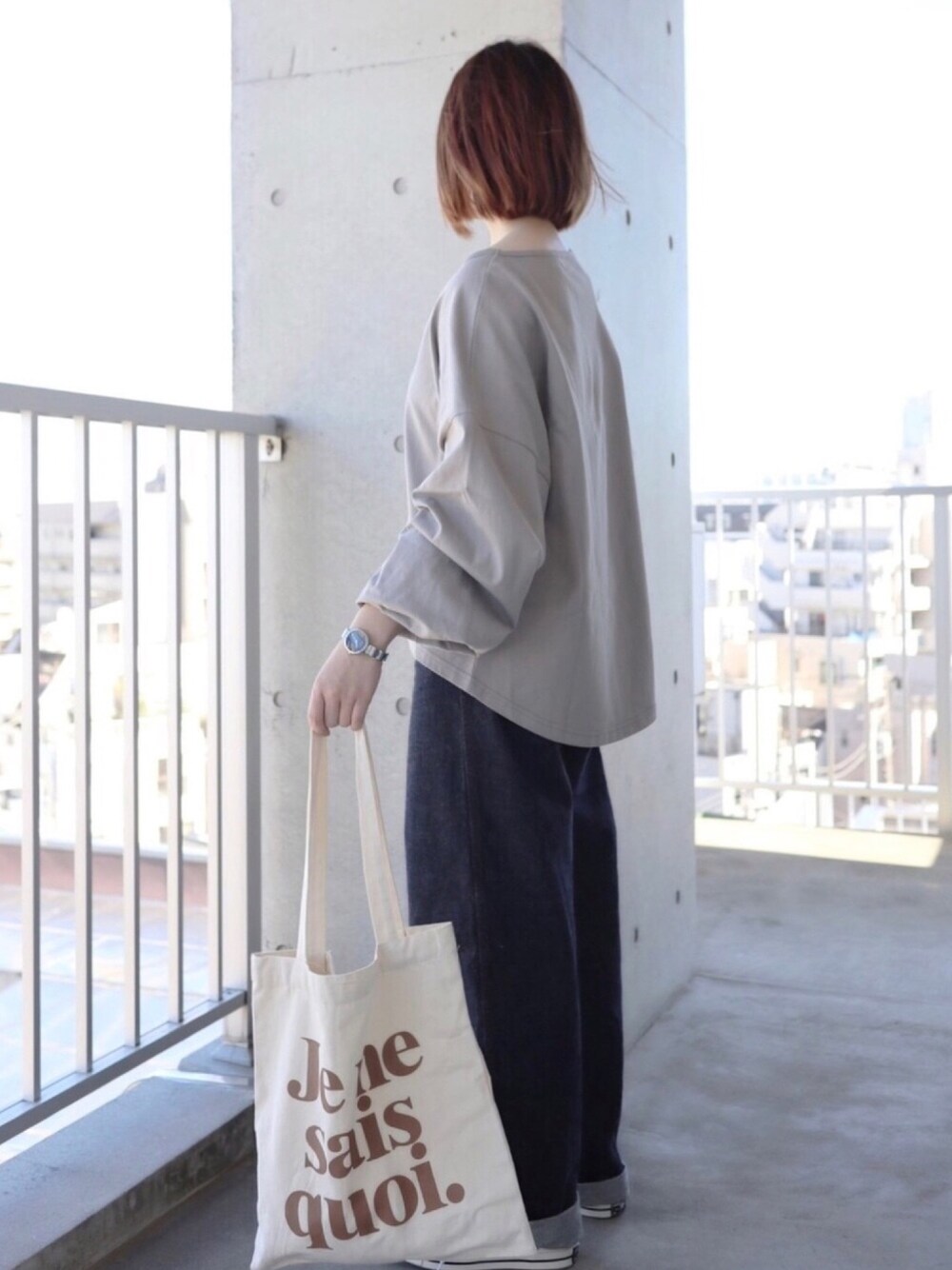 ブルー系のデニムパンツ、ベージュ系のトートバッグ、ブラック系のスニーカーを着用したレディースの秋コーディネートの1枚目の写真