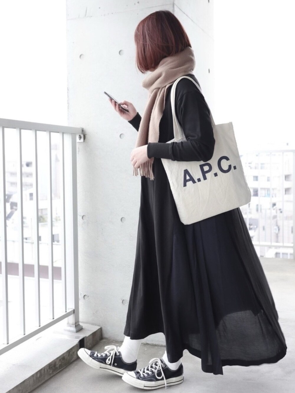 ブラック系のワンピース、ブラック系のスニーカー、ベージュ系のストール/ショールを着用したレディースの冬コーディネートの1枚目の写真