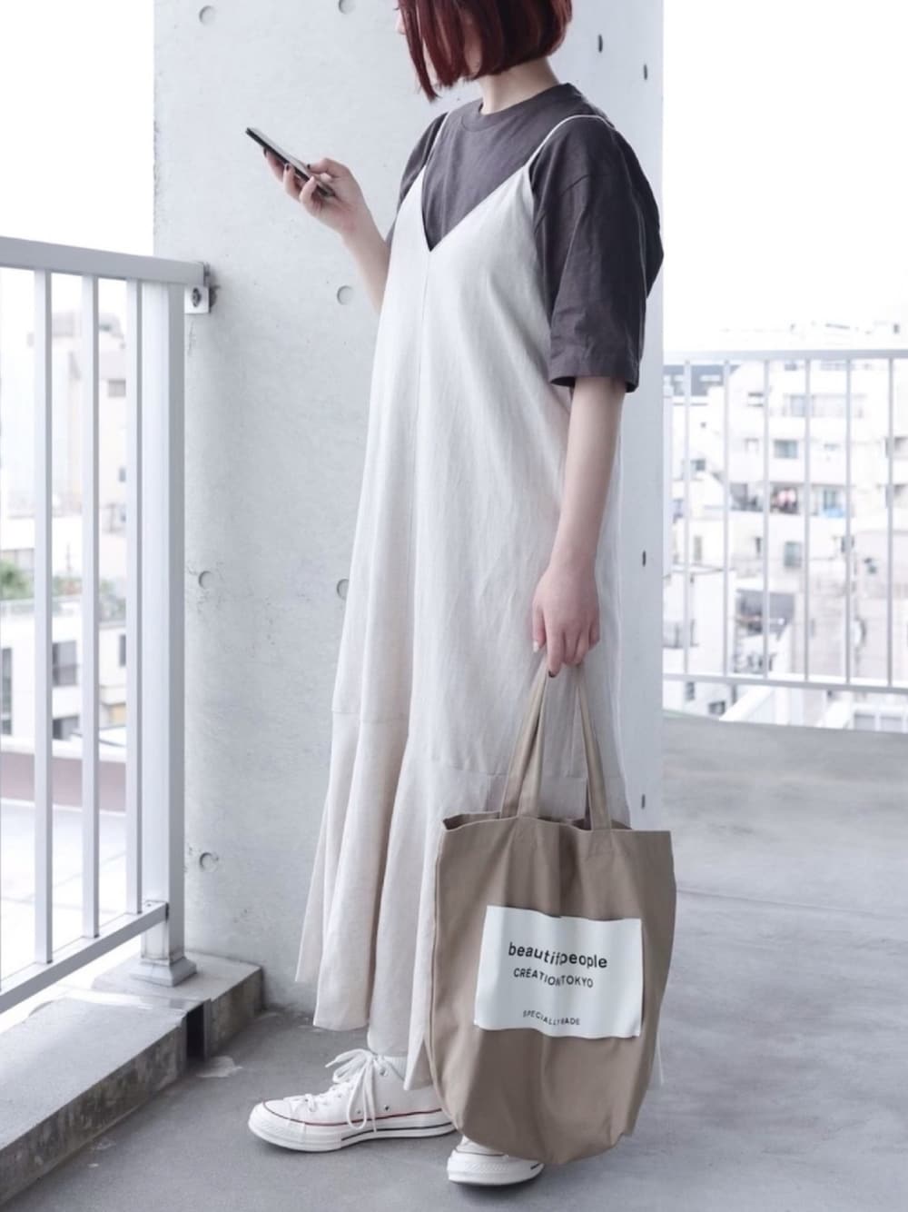 ベージュ系のワンピース、ブラウン系のTシャツ/カットソー、ベージュ系のトートバッグを着用したレディースの春コーディネートの1枚目の写真