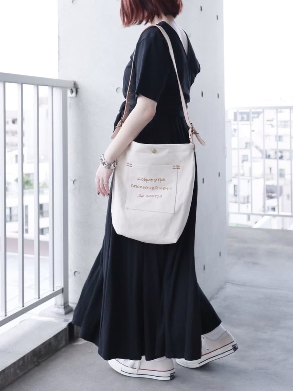 ベージュ系のショルダーバッグ、ブラック系のワンピース、ホワイト系のスニーカーを着用したレディースの夏コーディネートの1枚目の写真