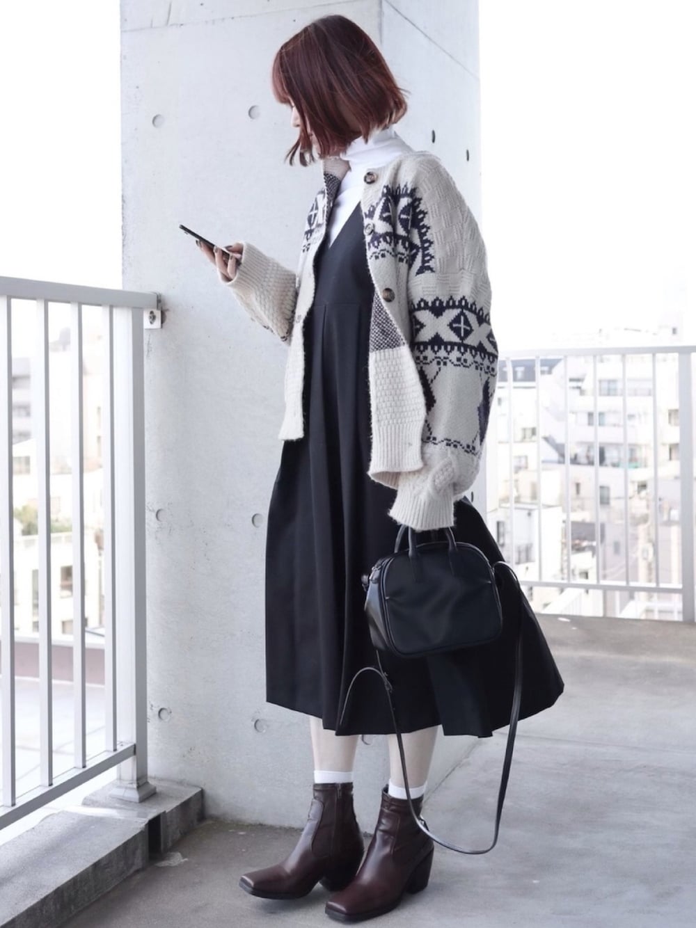 ブラック系のワンピース、ホワイト系のカーディガン/ボレロ、ホワイト系のTシャツ/カットソーを着用したレディースの冬コーディネートの1枚目の写真
