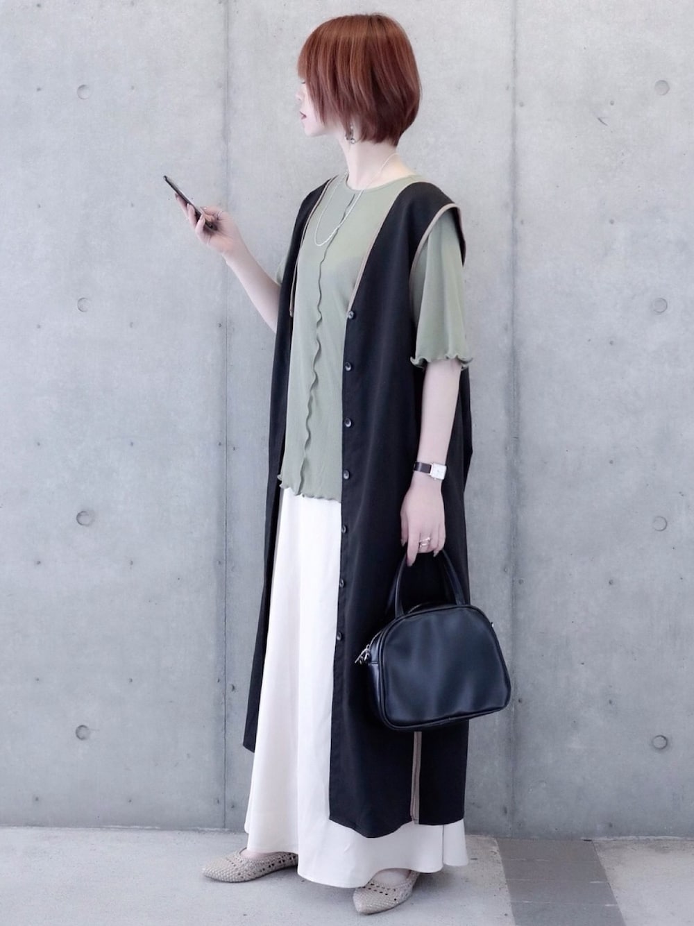 グリーン系のTシャツ/カットソー、ブラック系のワンピース、ホワイト系のスカートを着用したレディースの春コーディネートの1枚目の写真