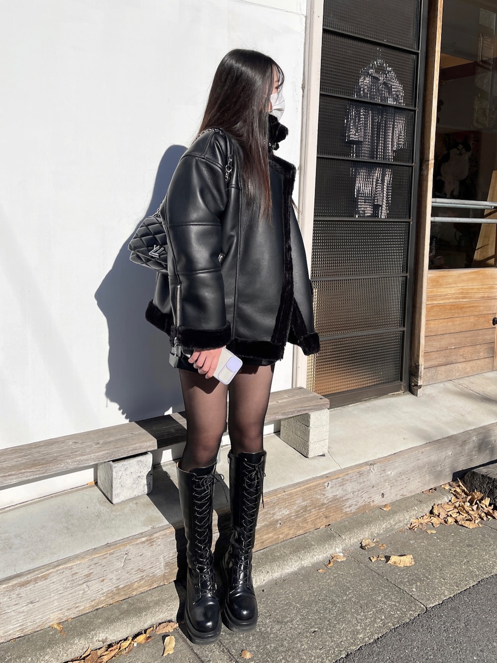 ブラック系のムートンコート、ブラック系のバッグ、ブラック系のブーツを着用したレディースの冬コーディネートの1枚目の写真