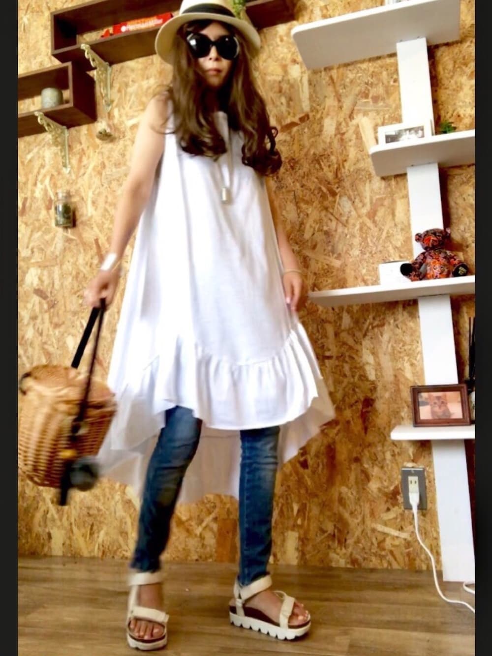 ホワイト系のワンピース、ブルー系のデニムパンツ、ブラック系のかごバッグを着用したレディースの夏コーディネートの1枚目の写真