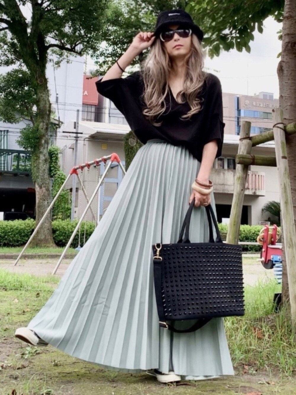 ブラック系のニット/セーター、グリーン系のスカート、ブラック系のトートバッグを着用したレディースの夏コーディネートの1枚目の写真