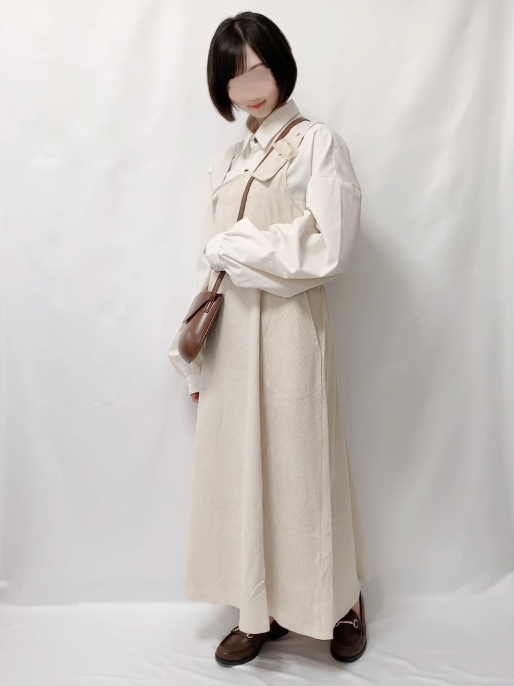 ホワイト系のシャツ/ブラウス、ホワイト系のジャンパースカート、ブラウン系のショルダーバッグを着用したレディースの秋コーディネートの1枚目の写真